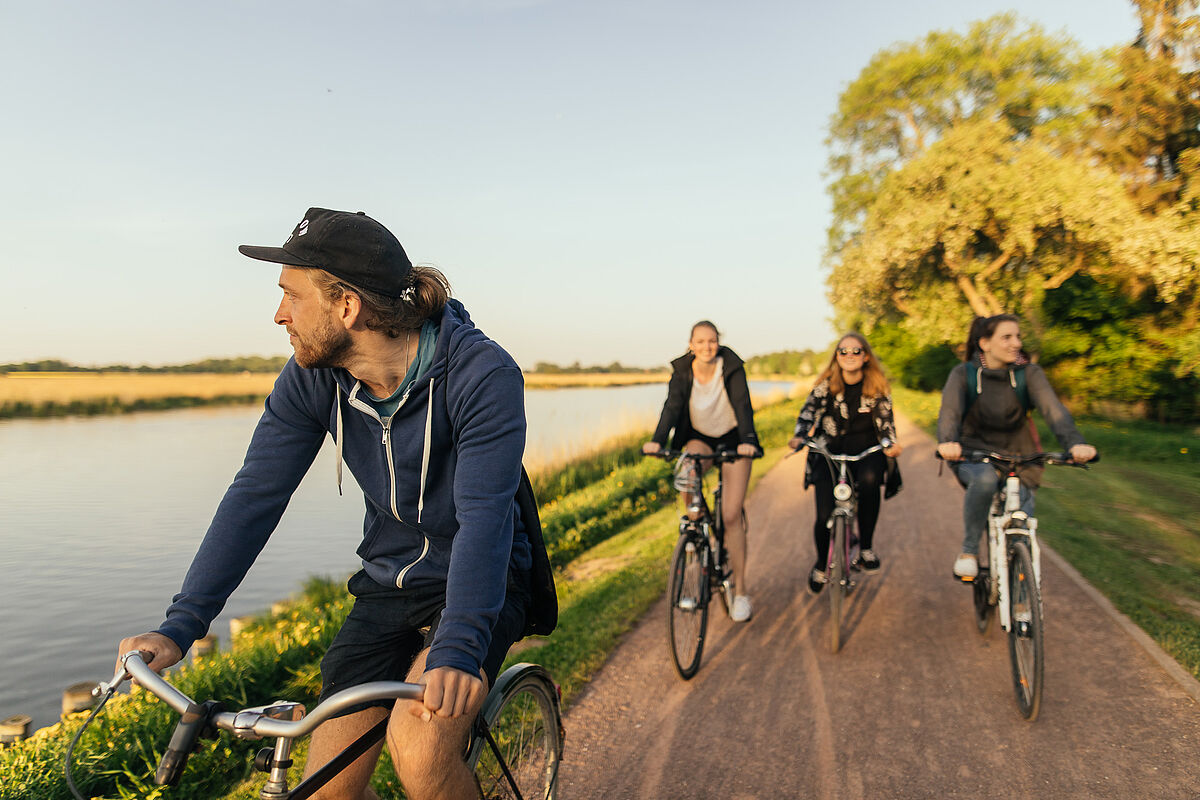 Eine Gruppe Radfahrer*innen auf dem Treidelpfad am Flüsschen Ryck.